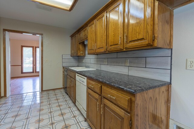 kitchen featuring decorative backsplash, dark stone counters, and white dishwasher