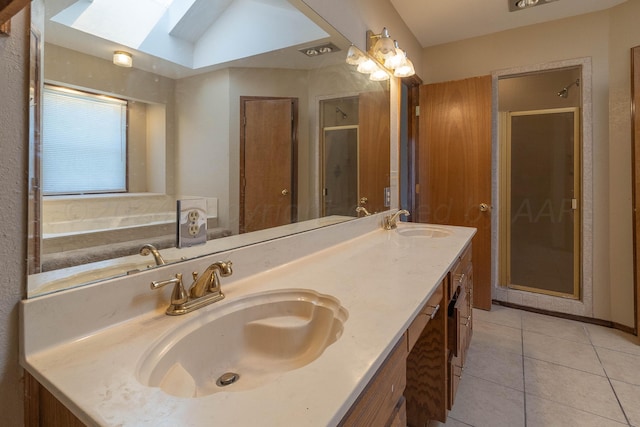 bathroom with vanity, vaulted ceiling with skylight, tile patterned flooring, and a bathing tub