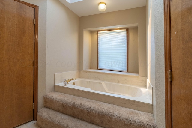 bathroom with a tub and a skylight