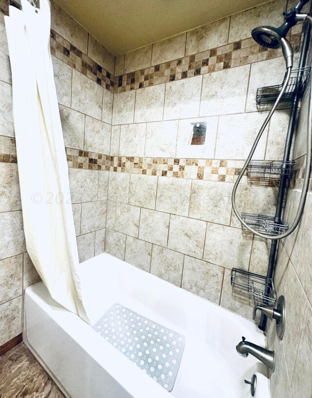 bathroom with hardwood / wood-style floors and shower / bath combination with curtain