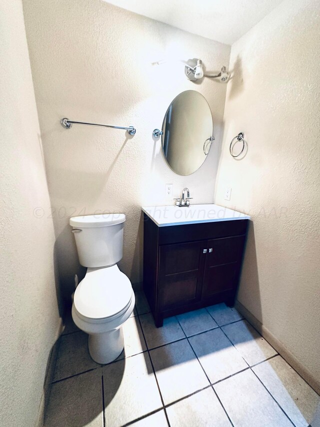 bathroom with toilet, vanity, and tile patterned floors