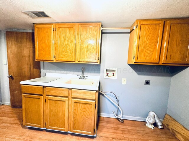 washroom featuring cabinets, light hardwood / wood-style floors, sink, hookup for an electric dryer, and hookup for a washing machine