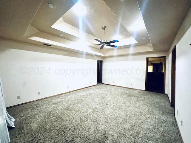 interior space featuring carpet, ceiling fan, and a raised ceiling