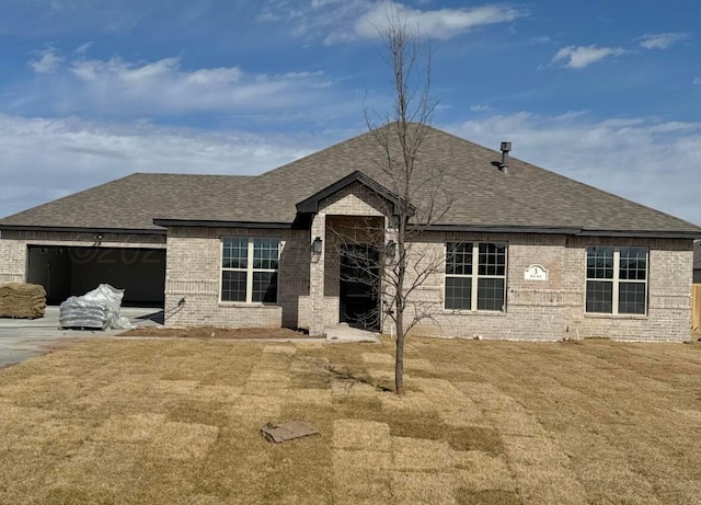 single story home with brick siding, a shingled roof, concrete driveway, a front yard, and an attached garage