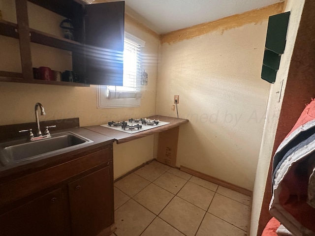 316 SE 21st Ave, Amarillo, TX 79109 - kitchen featuring dark brown cabinetry, white cooktop, a sink, light tile patterned floors, and baseboards