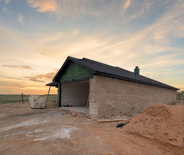 view of side of property featuring brick siding and a garage