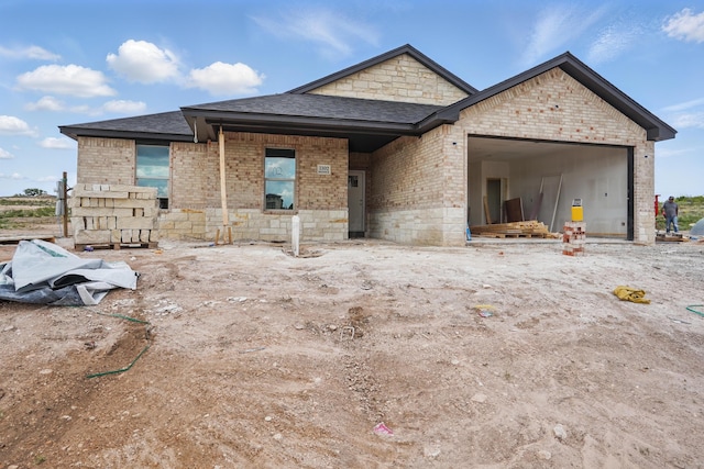 view of front of house featuring brick siding, an attached garage, and a shingled roof
