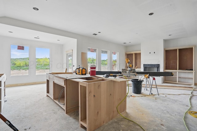 kitchen with a fireplace, a kitchen island, recessed lighting, and baseboards