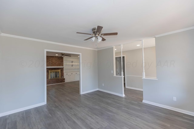 unfurnished room featuring dark wood-type flooring, ceiling fan, a brick fireplace, and crown molding