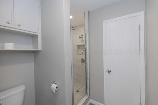 bathroom featuring toilet and a shower with shower door