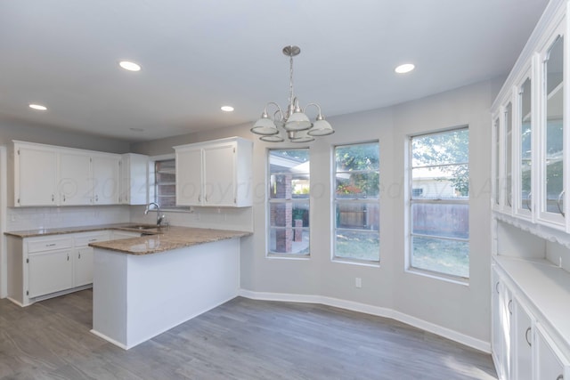 kitchen with dark hardwood / wood-style floors, white cabinetry, sink, and kitchen peninsula