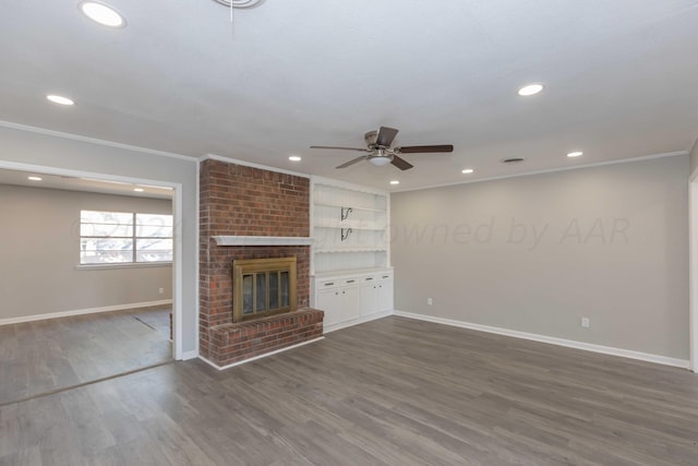 unfurnished living room featuring dark wood-type flooring, ceiling fan, crown molding, and a brick fireplace