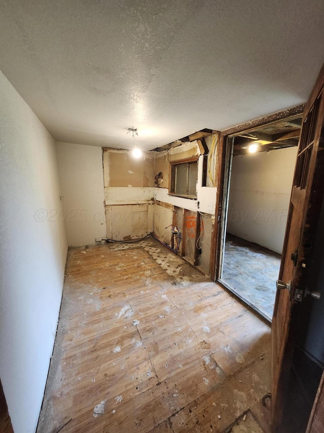 unfurnished room with light wood finished floors and a textured ceiling