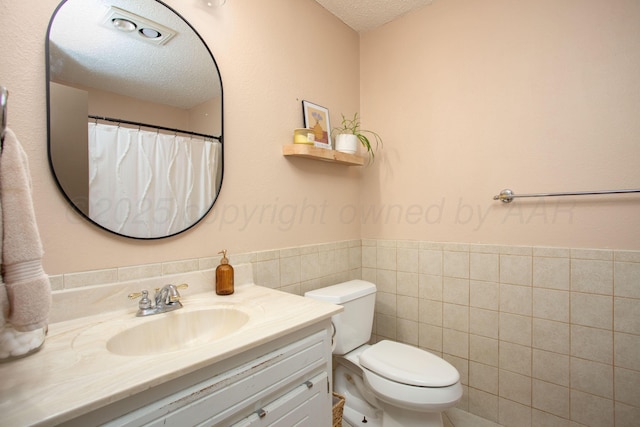 4818 SE 33rd Ave, Amarillo, TX 79103 - full bath with a textured ceiling, vanity, tile walls, and a wainscoted wall
