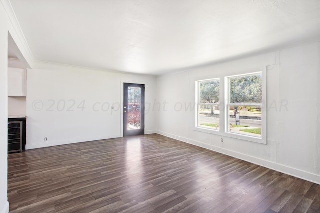 818 N Someville St, Pampa, TX 79065 - unfurnished living room with wine cooler, baseboards, ornamental molding, and dark wood-type flooring