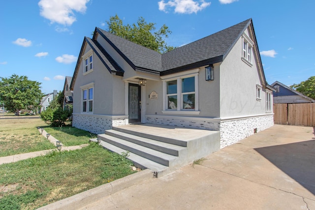 818 N Someville St, Pampa, TX 79065 - view of front facade featuring a shingled roof, a front lawn, stucco siding, and fence