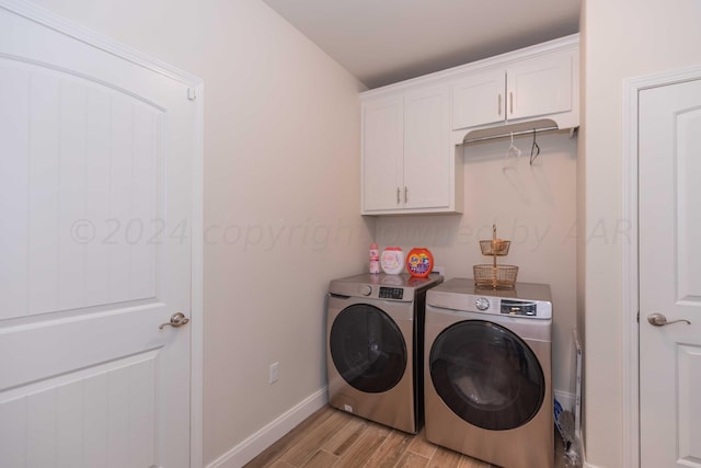 washroom featuring cabinet space, baseboards, washing machine and dryer, and light wood-style floors