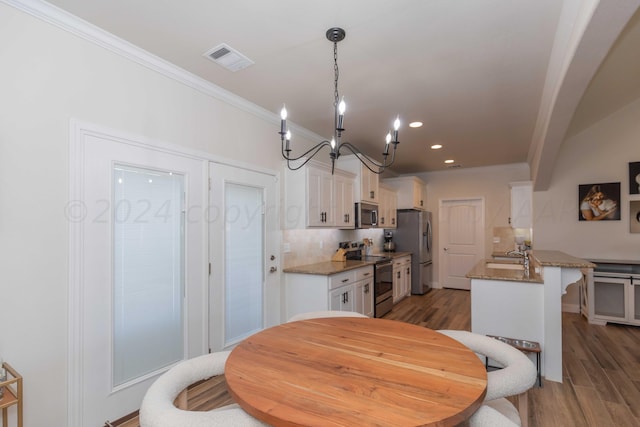 dining area with a chandelier, recessed lighting, light wood-style flooring, crown molding, and visible vents