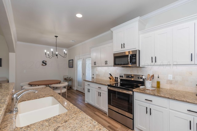 kitchen featuring stainless steel appliances, light wood finished floors, a sink, and backsplash