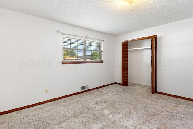 unfurnished bedroom with a closet, baseboards, a textured ceiling, visible vents, and carpet