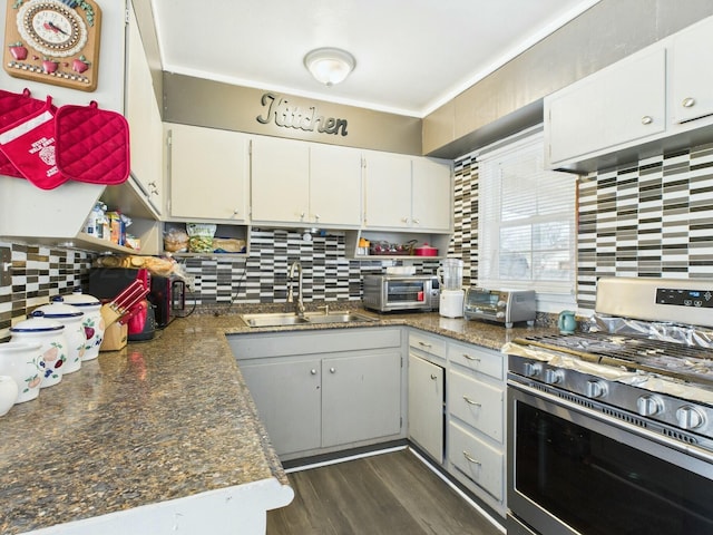 kitchen with a sink, white cabinets, gas range, and tasteful backsplash