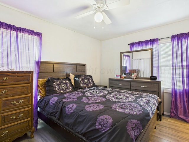 bedroom with a ceiling fan, multiple windows, and wood finished floors