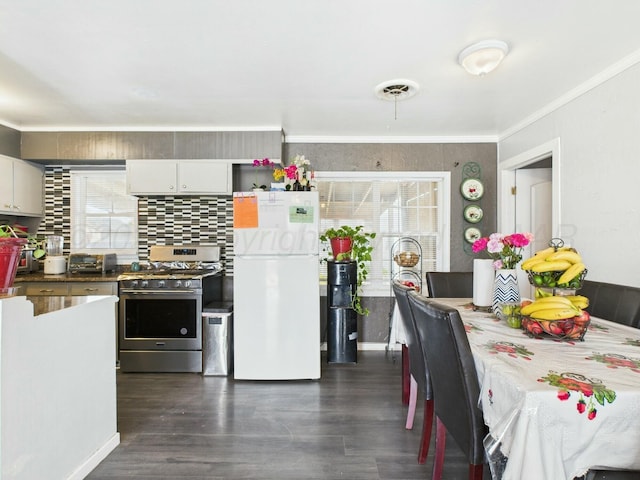 kitchen with visible vents, crown molding, gas stove, dark wood-type flooring, and freestanding refrigerator