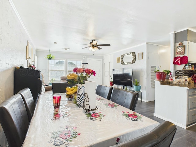 dining room featuring ornamental molding, baseboards, ceiling fan, a textured wall, and dark wood-style flooring