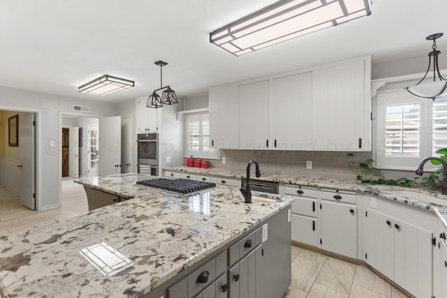 kitchen with decorative light fixtures, white cabinetry, and sink