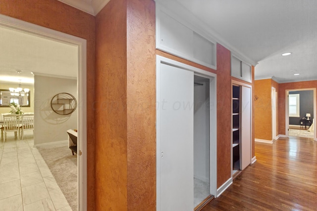 hall with a chandelier, ornamental molding, and hardwood / wood-style flooring