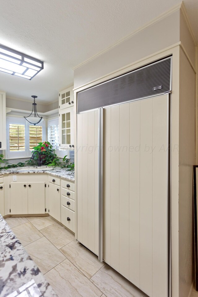 kitchen with light stone counters, sink, white cabinets, and a textured ceiling