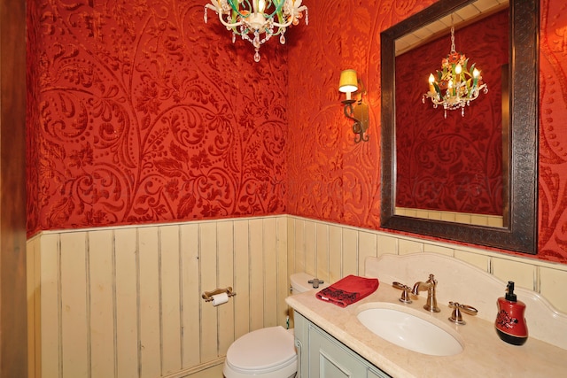 bathroom with toilet, vanity, and a notable chandelier