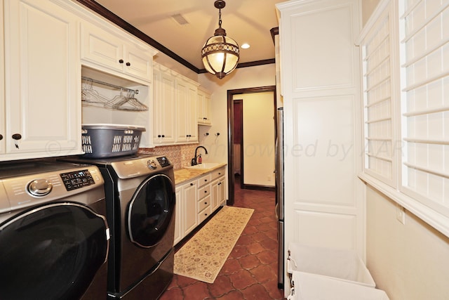 laundry area with separate washer and dryer, crown molding, dark tile patterned floors, cabinets, and sink