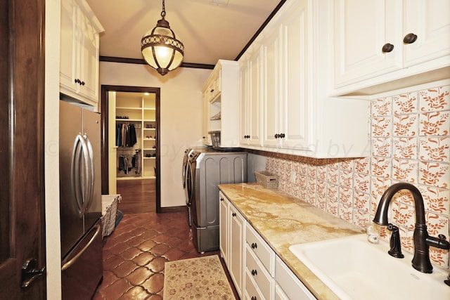 laundry area featuring cabinets, separate washer and dryer, sink, dark tile patterned floors, and crown molding