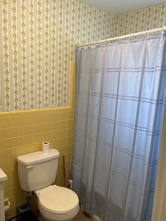 bathroom featuring toilet and tile walls