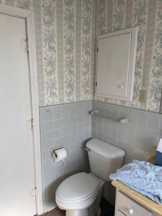 bathroom featuring vanity, toilet, and tile walls