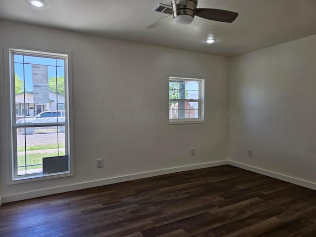spare room featuring ceiling fan, baseboards, visible vents, and dark wood finished floors
