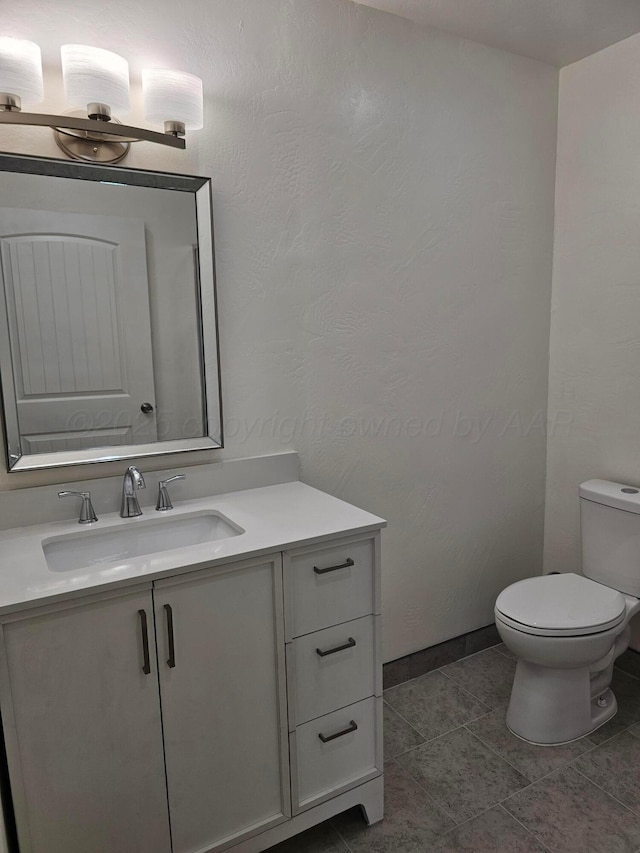 half bath with toilet, baseboards, tile patterned flooring, and vanity