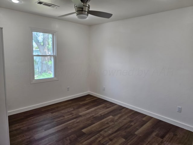 empty room with baseboards, ceiling fan, visible vents, and dark wood-style floors
