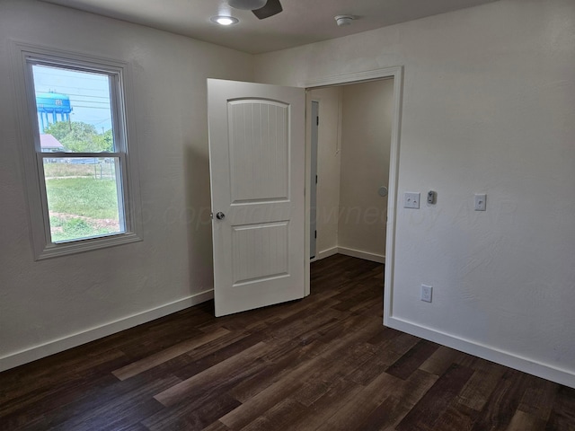 empty room featuring baseboards, a ceiling fan, and dark wood-style floors
