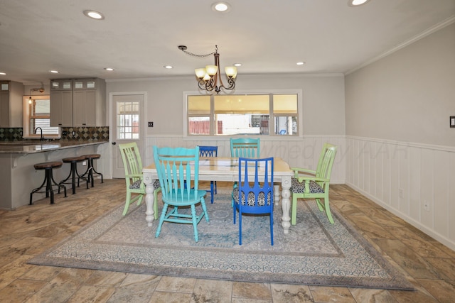 dining area featuring crown molding, sink, and an inviting chandelier