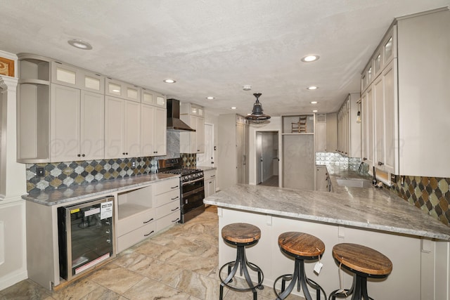 kitchen with sink, double oven range, beverage cooler, kitchen peninsula, and wall chimney exhaust hood