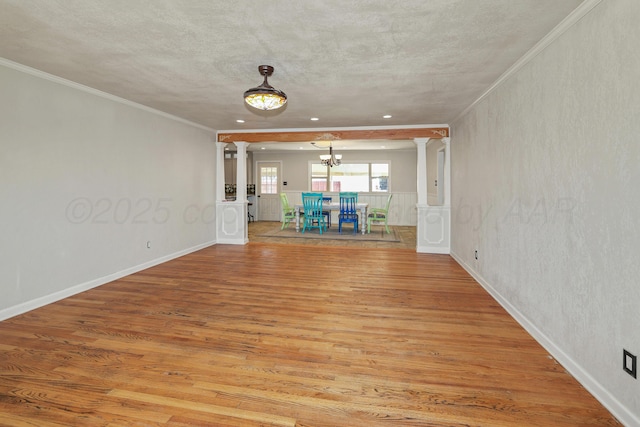 interior space with crown molding, light hardwood / wood-style flooring, decorative columns, a textured ceiling, and a chandelier