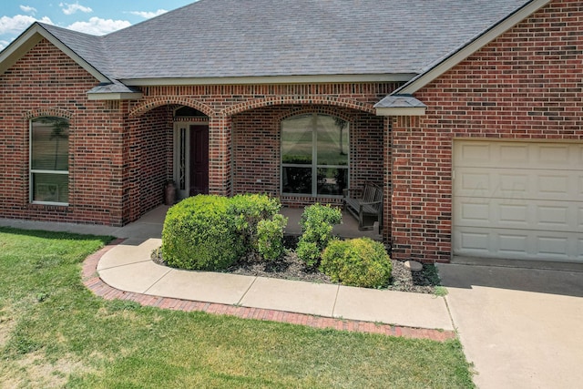 entrance to property with a garage and a lawn