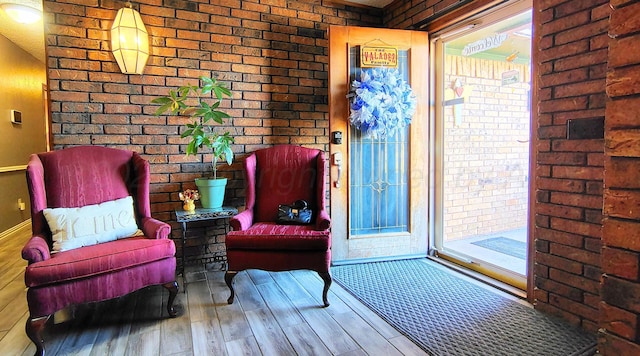 living area featuring brick wall and hardwood / wood-style floors