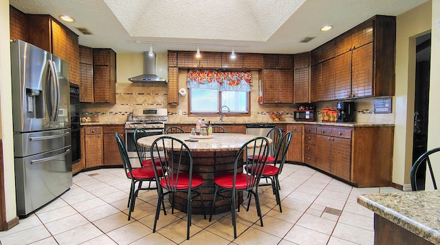 406 Bradley Ln, Dumas, TX 79029 - kitchen featuring tasteful backsplash, appliances with stainless steel finishes, wall chimney range hood, and light tile patterned floors