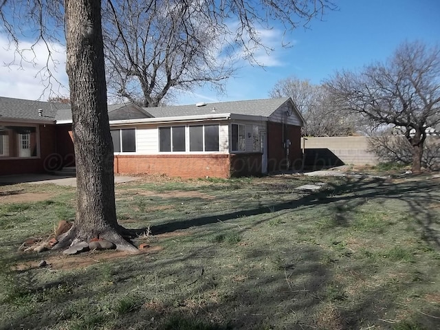 view of property exterior featuring brick siding and fence