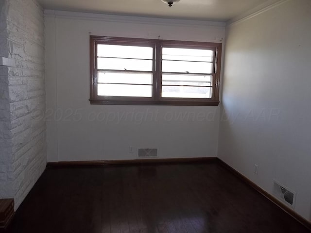 empty room featuring dark wood-style flooring, baseboards, and visible vents