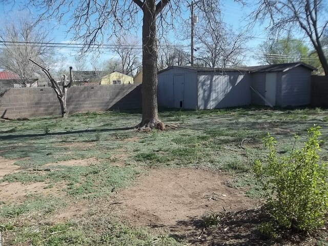 view of yard featuring an outdoor structure, fence, and a storage shed