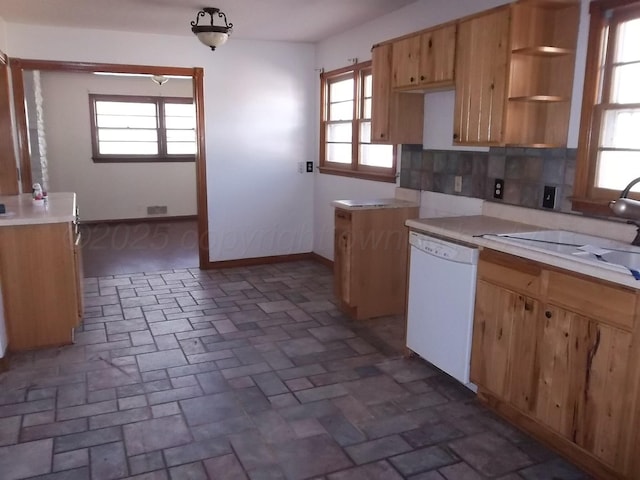 kitchen featuring plenty of natural light, white dishwasher, baseboards, and decorative backsplash